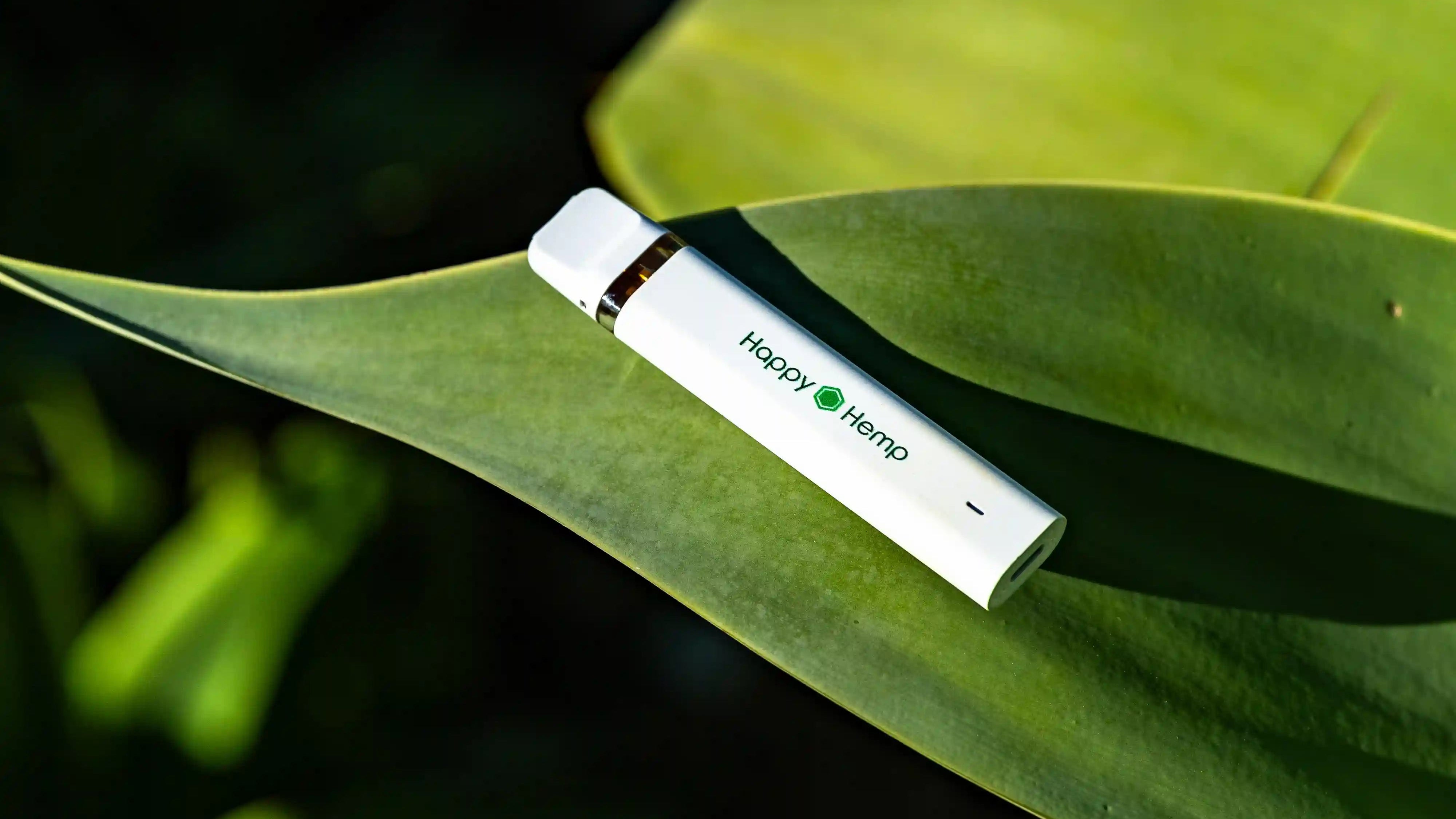 H3 Ultra Vape Pen liegt auf einem grünen Pflanzenblatt, wird von der Sonne angestrahlt und wirft einen Schatten
