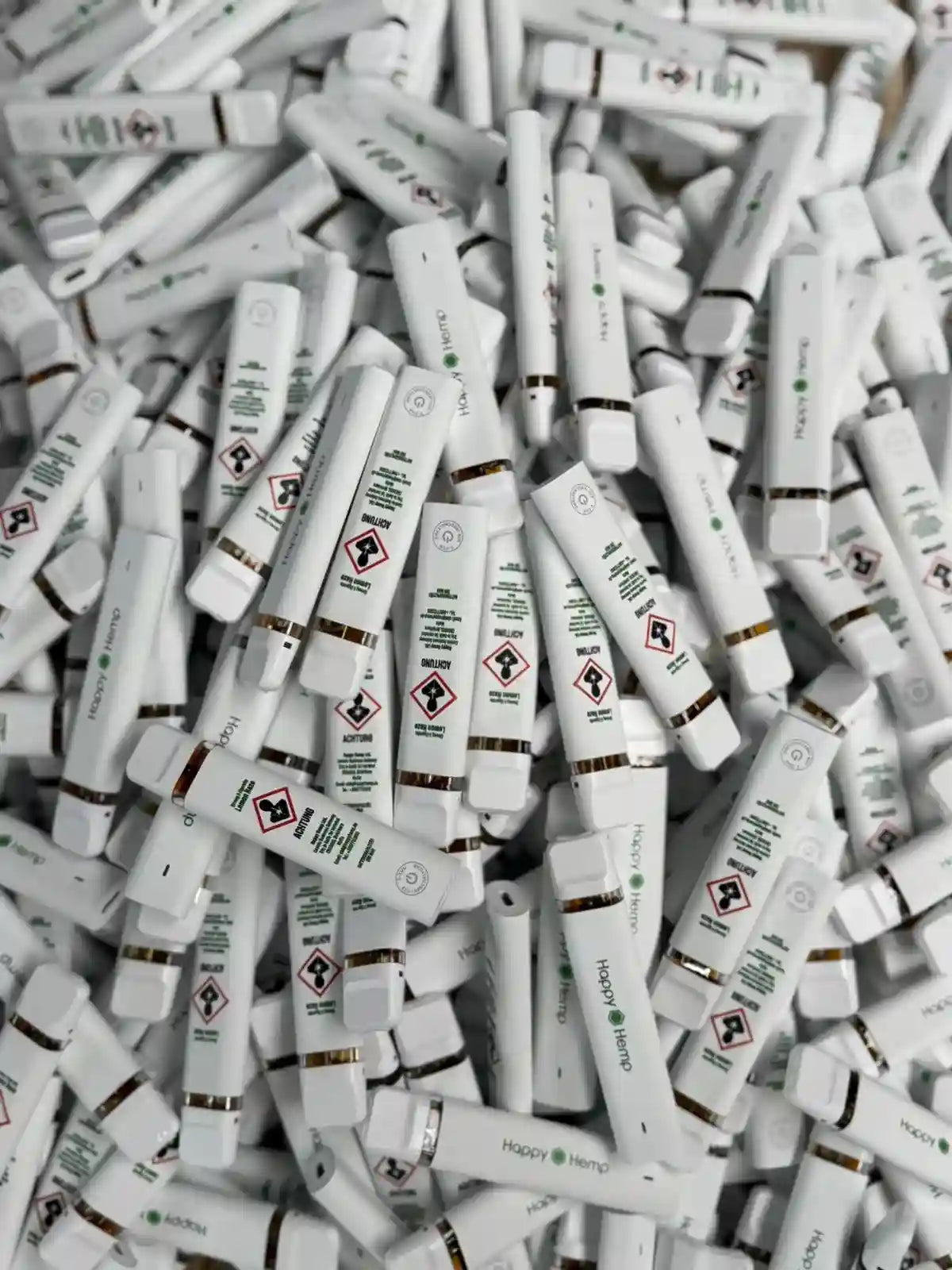 Viele weiße H3 Ultra Vape Pens liegen auf einem Haufen. Auf der Rückseite sind Sicherheitshinweise zu sehen.