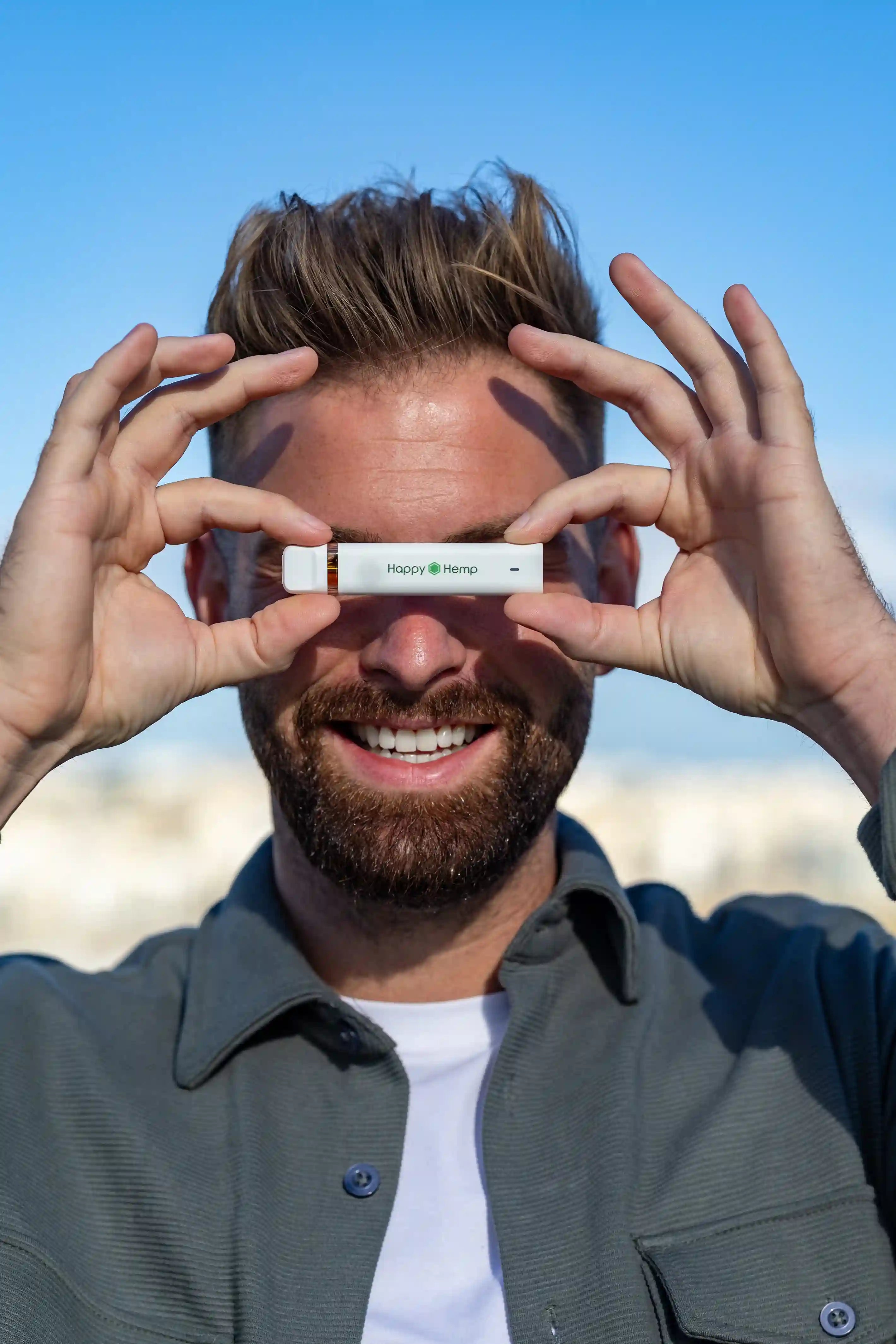 Ein grinsender Mann hält den H3 Ultra Vape Pen in beiden Händen waagerecht und verdeckt damit seine Augen